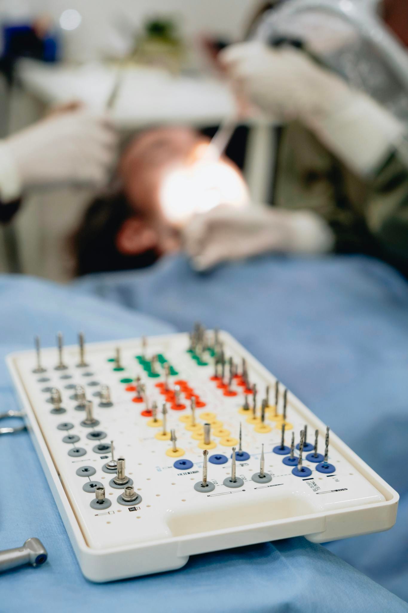 Close-up of a dental implant kit with dentist working on a patient in the background.